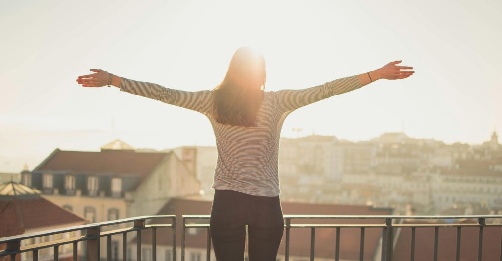 mujer con los brazos extendidos bajo el sol